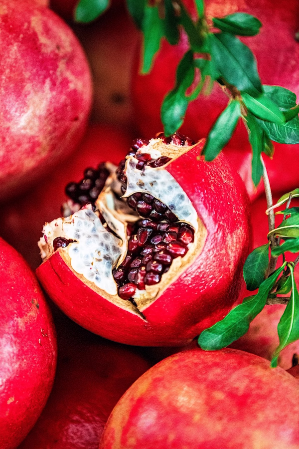 Close-up of ripe pomegranates, including one opened to reveal vitamin C rich red seeds known to support immune health.